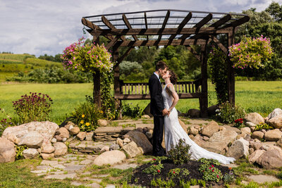 Bride and groom kiss under a pergola at CHQ Barn in Chautauqua NY