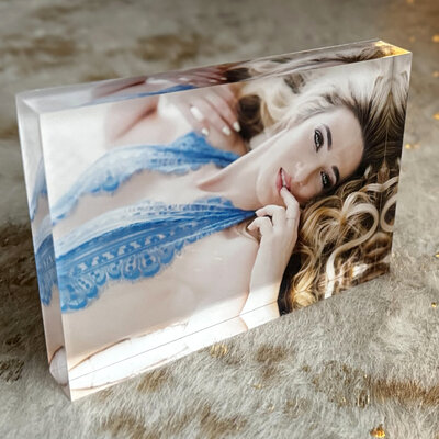 3d Ice Block of a woman wearing a blue lace body suit, lying on the ground with her blonde hair flowing all around her