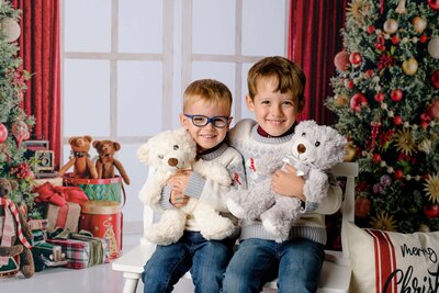 little boys holding teddy bears pose in a holiday set up