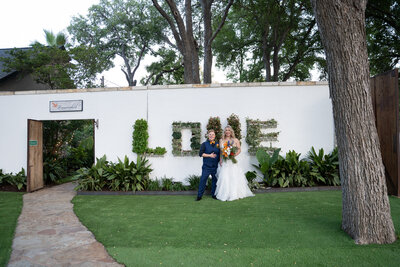 Austin-based wedding photographer captures a bride and groom standing in front of a sign that says love.