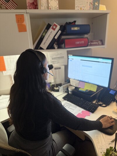 woman sitting at desk with a headset on working on the computer
