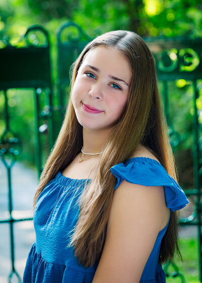 girl wearing blue for her senior photos by a beautiful gate