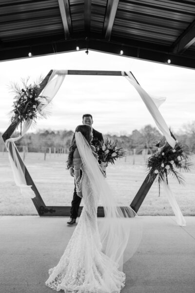 Bride and groom stand under their wedding arch