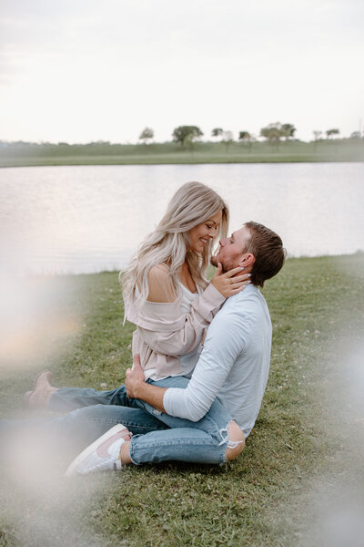 Girl sitting on fiance while grabbing his neck looking into eyes