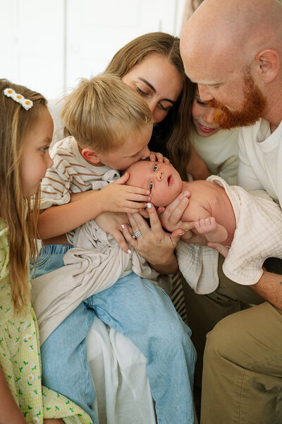 Family holding and kissing newborn baby