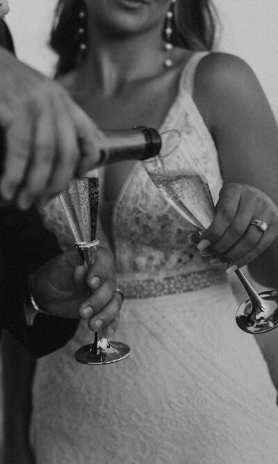 bride and groom celebrate wedding day with bottle of champagne