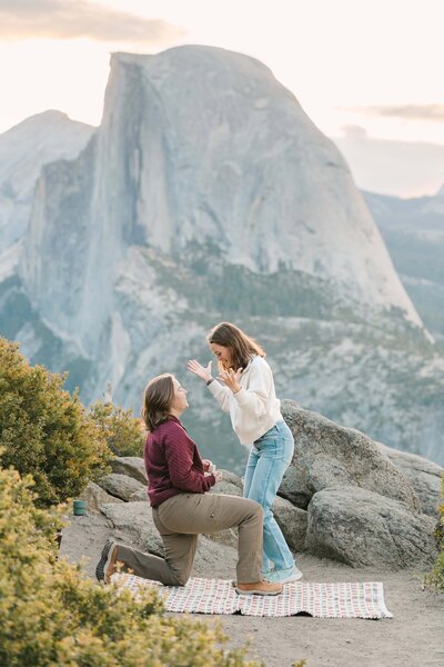 Hiker is on one knee  proposing at glacier point in Yosemite national park during sunrise with half dome in the background