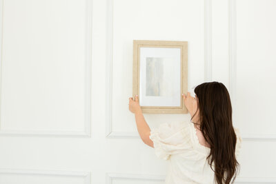 Photographer hanging portraits in a gallery wall