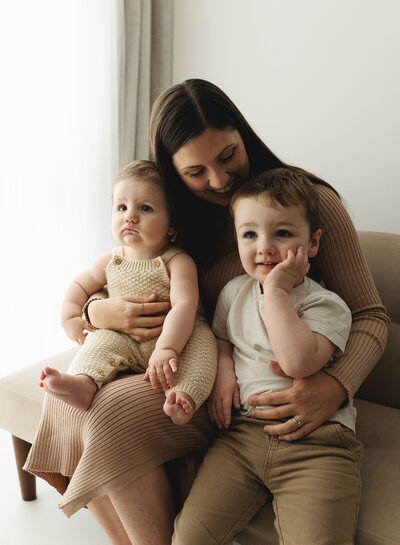 Family cuddling on studio sofa during natural lifestyle session in Poole, Dorset