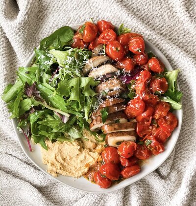 Bowl with salad greens, tomatoes, mushrooms, and hummus