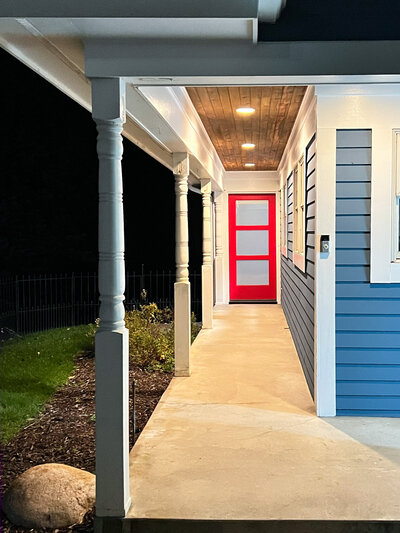 House with blue siding, red front door and concrete floor