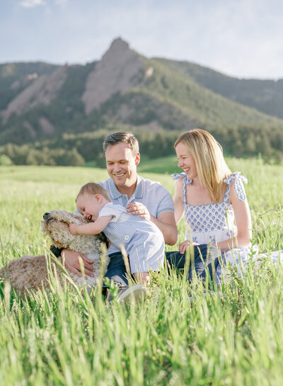 A family of three with their dog with the Boulder Flatirons in the Background
