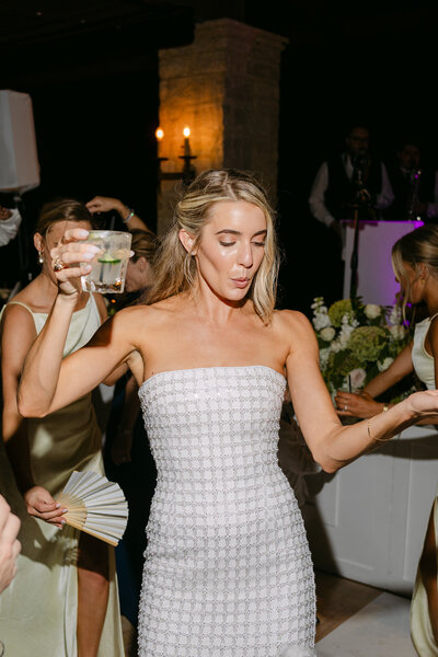 Bride and short white dress dancing at receiption while bridesmaids cheer in background