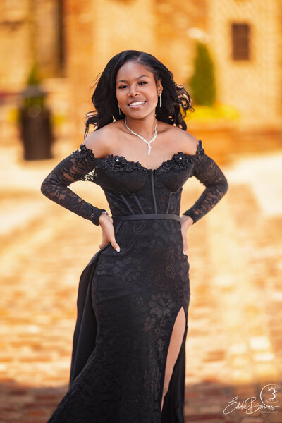 A young woman poses outdoors in a black gown with bright pink shoes, photographed by a Simpsonville photographer."