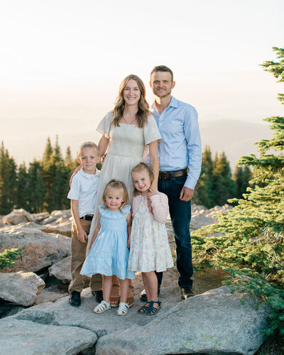 Coeur d'Alene photographer documents family of four in festive holiday attire during winter portrait session in snowy forest