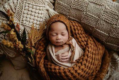 Newborn in wooden crib with palm trees