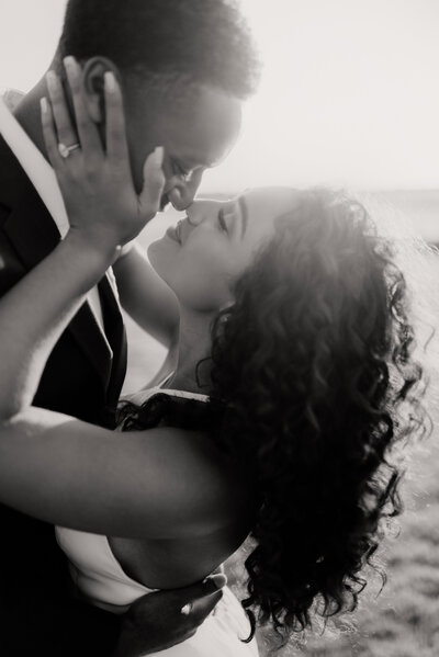 black and white image of bride and groom touching noses with their eyes closed during an intimate moment at sunset at The Barn at Grace Hill in Wichita Kansas