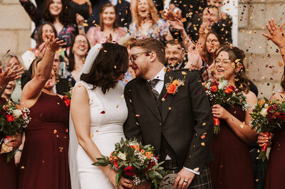 Bride and bridesmaids laughing under confetti at aswanley wedding venue