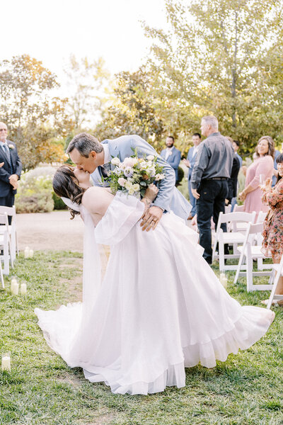 A groom dips his bride during their ceremony for a kiss at their Sacramento park winters wedding.