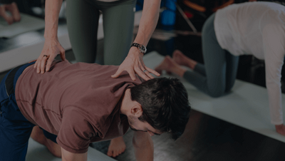 man doing cat cow in a pilates class 