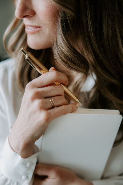 A woman holding a notebook and pen for website copywriting
