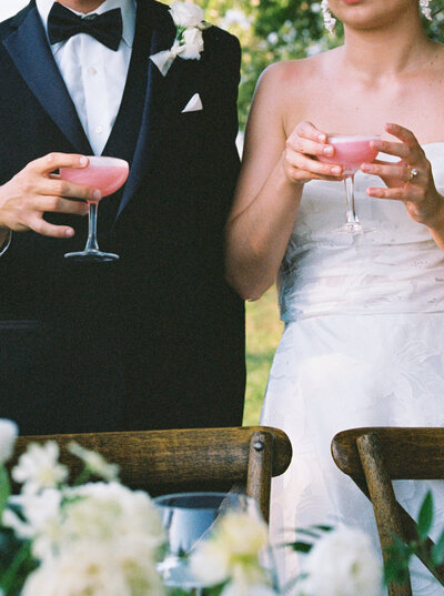 close up of bride and groom holding pink drinks
