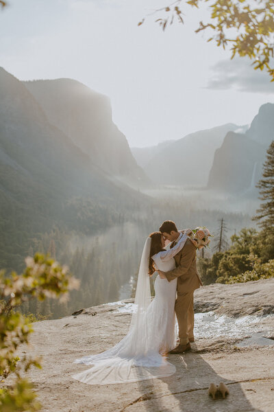 bride and groom embrace overlooking yosemite valley during elopement