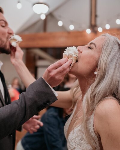 bride and groom feed cupcakes to each other