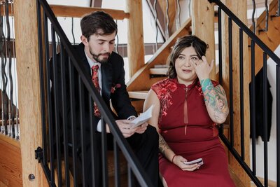 Bride  in red dress cries as groom reads private vows during Airbnb elopement.