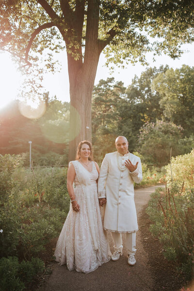 Indian/Jewish wedding couple photographed during golden hour nestled on the nearby walkway surrounded by flowers and plants in Bartrams Garden's Philadelphia.