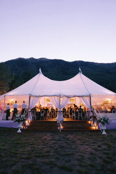 Wedding events tent lit in the evening with a mountain backdrop