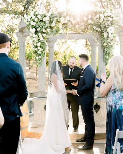 Portrait of Bride + Groom holding hands at the altar