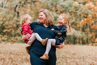 mom holding two toddler girls, laughing together