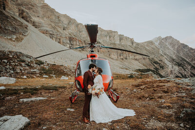 photo of couple kissingin front of helicopter that was part of their Banff elopement package