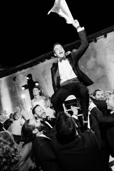 Bride and groom held on the shoulders of their guests while partying at a Tuscany villa in Italy.