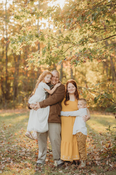 Blacksburg, Virginia Photographer, Melena Lawson, and her family embrace one another and smile at the camera.