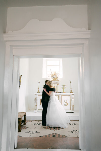 A couple hugging in the chapel of Bishop's Lodge Resort in Santa Fe