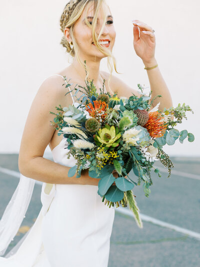 bride laughing with hair in her face holding her bouquet