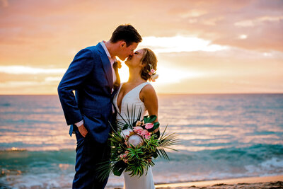bride and groom kiss at sunset on their wedding day on a Maui beach