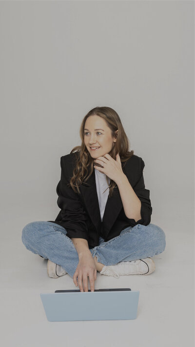 Designer sat on the floor with a cup of tea and laptop smiling