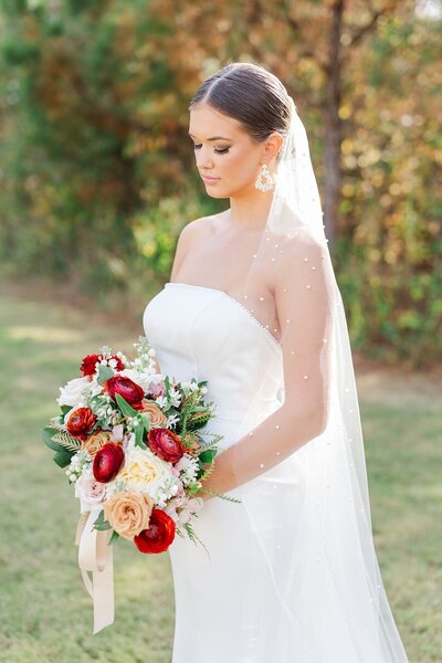 Stunning bride looks down at her wedding bouquet
