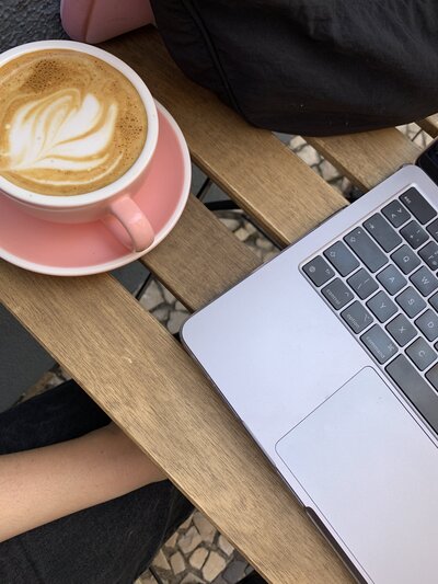 Laptop and pink mug of coffee on a wooden table