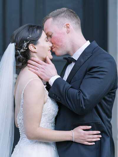 Bride and groom kissing at black tie wedding on country estate