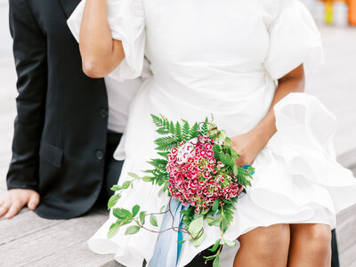 closeup of bridal bouquet with bride and groom sitting in New York City