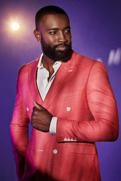 Dillard wearing a bold red jacket, posing confidently against a purple backdrop, captured by Ylva Erevall.