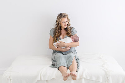Close-up of a baby's face and hand resting on a soft white fabric. The focus is on the babys lips and tiny fingers, conveying a peaceful and gentle mood. The soft fabric adds to the cozy and serene atmosphere.