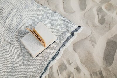 book on a blanket in the sand