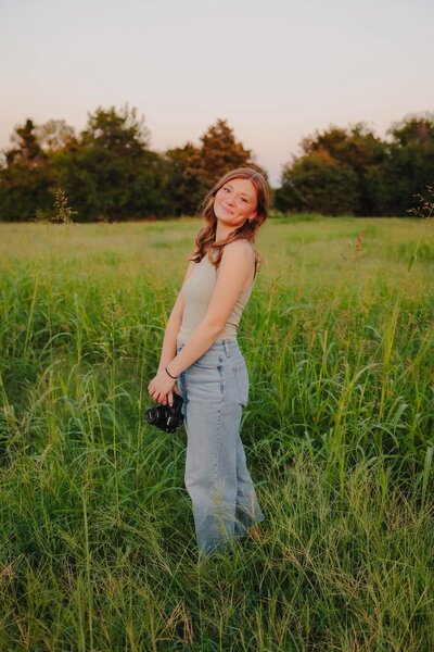 sydney chapman holding camera in a field