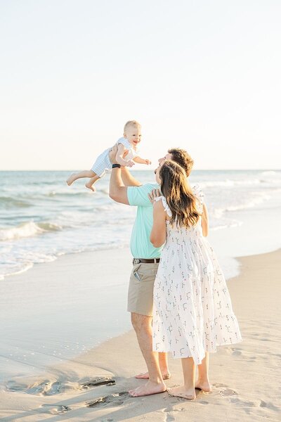 parents holding toddler by ocean at Emerald Isle Atlantic beach during family photos