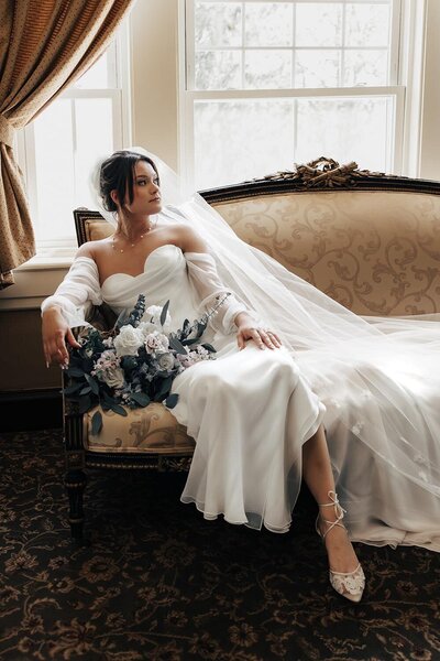 bride sitting on vintage couch in her wedding dress in philadelphia
